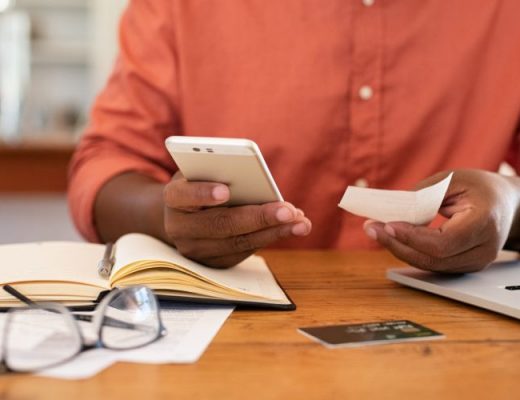man holding a receipt and entering reimbursement request into his phone using mobile expense management program